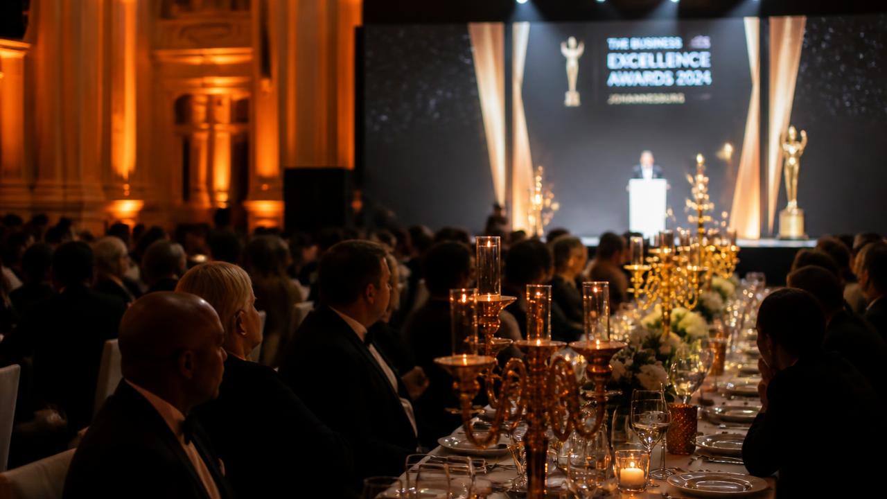 Black-tie gala dinner in Johannesburg with banquet tables dressed by Memories in Motion under warm amber uplighting and a lit awards stage